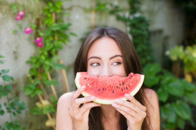 Smiling woman playing with watermelon
