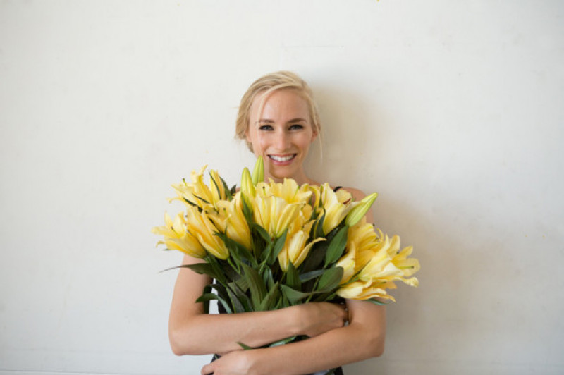 Portrait of young woman holding bouquet of yellow flowers