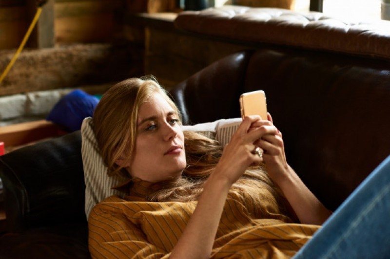 Portrait of woman concentrating on phone reclining on couch