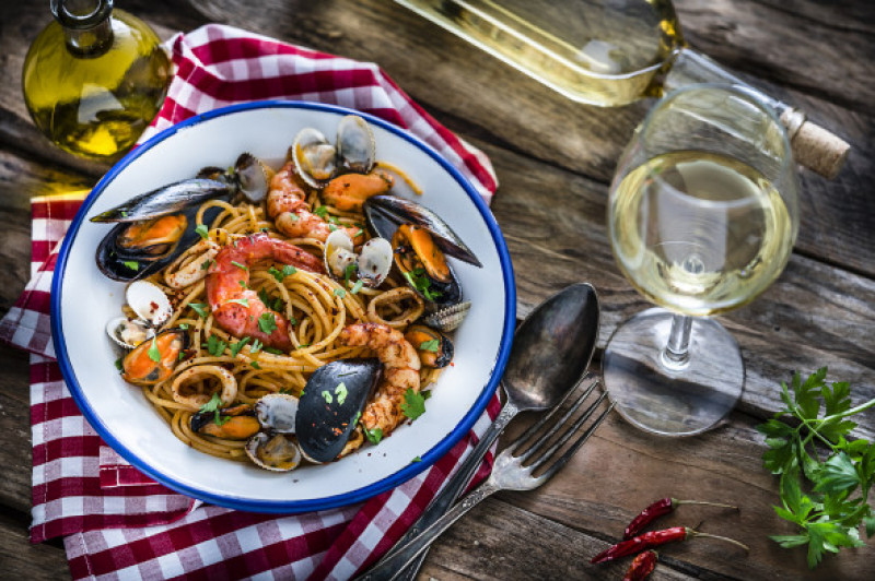 Italian food: seafood pasta and white wine on rustic wooden table