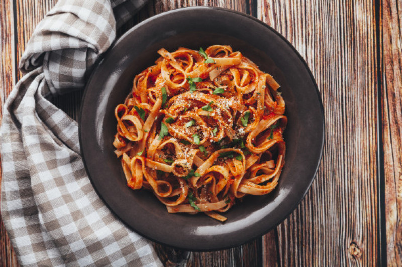 Tagliatelle  with tomato sauce on wooden background.