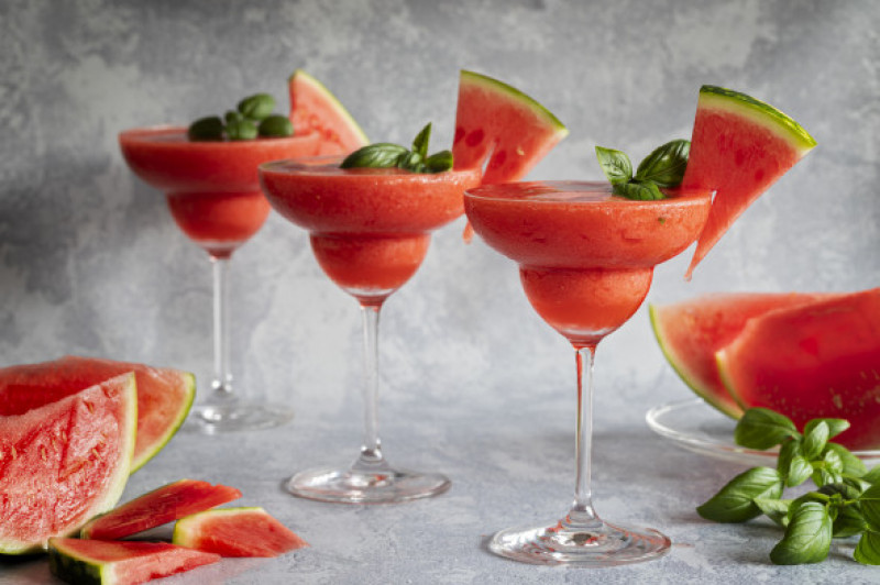 Frozen red drink margarita garnished with watermelon and basil. Three red drinks in a row.