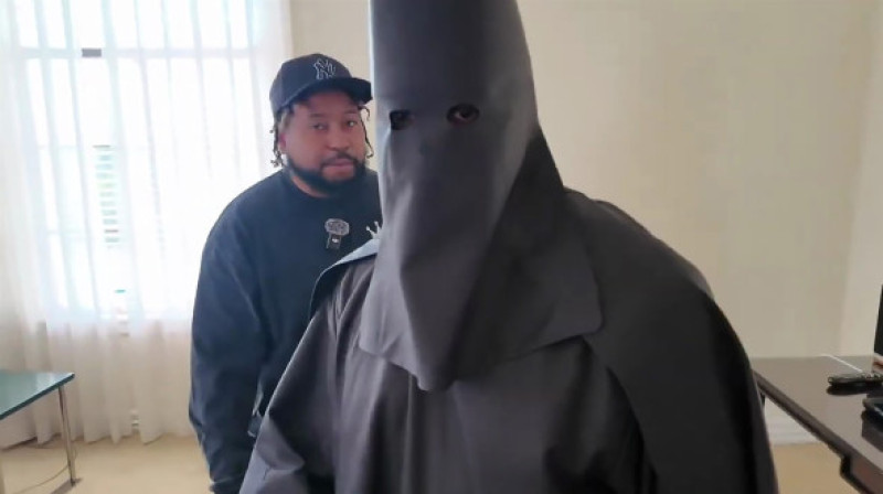 Kanye West wears a black KKK-inspired robe and hood with a swastika necklace and a Sean Jean t-shirt during an interview with DJ Akademiks