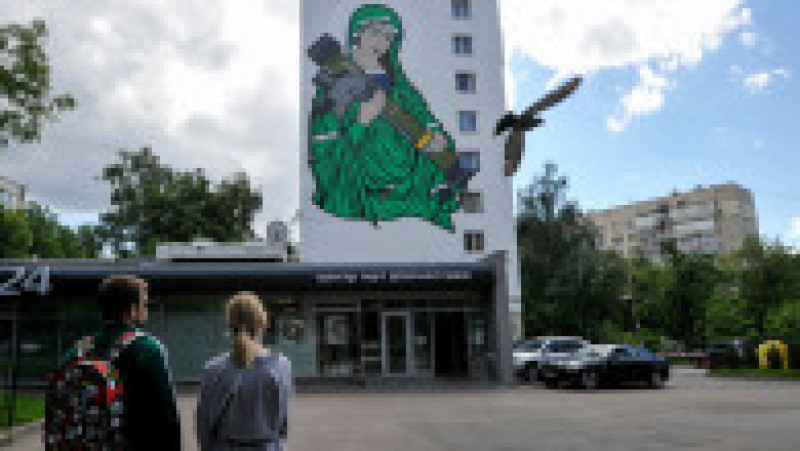 Oamenii se uită la o pictură murală „Sfântul Javelin”, care este înfățișată pe o clădire de locuințe din Kiev.. FOTO: Profimedia Images | Poza 2 din 12