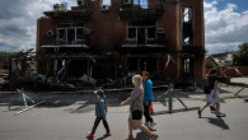 Oamenii trec pe lângă o casă distrusă care a fost avariată de bombardamentele armatei ruse în Makariv, la vest de capitala Ucrainei Kiev. Foto: Profimedia Images | Poza 9 din 10