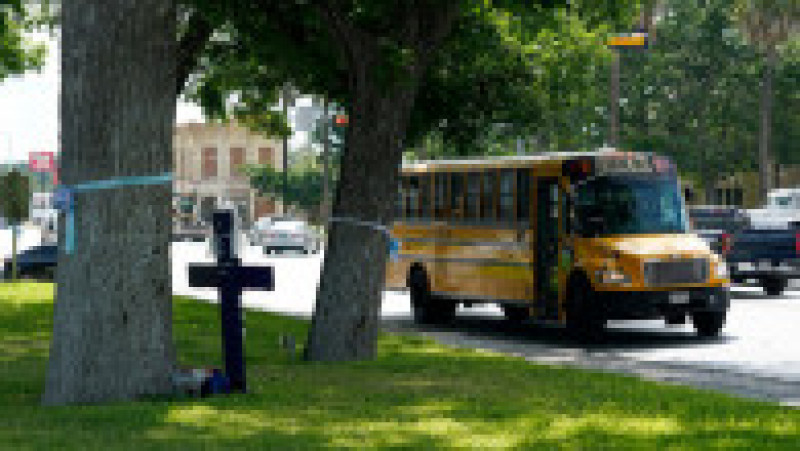 A school bus passes a cross placed in the city square to honor the victims killed in the recent school shooting at Robb Elementary, Thursday, June 9, 2022, in Uvalde, Texas. The Texas elementary school where a gunman killed 19 children and two teachers has long been a part of the fabric of the small city of Uvalde, a school attended by generations of families, and where the spark came that led to Hispanic parents and students to band together to fight discrimination over a half-century ago.,Image: 698449406, License: Rights-managed, Restrictions: This content is intended for editorial use only. For other uses, additional clearances may be required., Model Release: no, Credit line: Profimedia | Poza 8 din 11