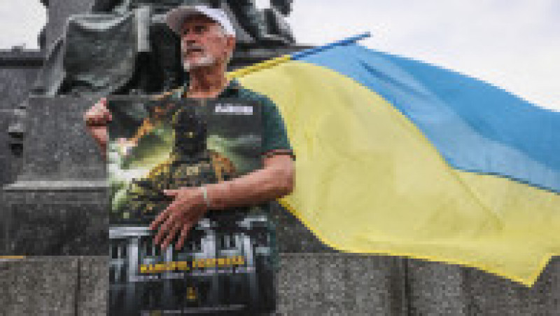 Un bărbat ține steagul ucrainean și un banner în timpul unei demonstrații de solidaritate cu Ucraina în piața principală din orașul polonez Cracovia. Foto: Profimedia Images | Poza 11 din 11