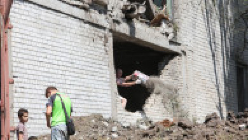 Un ucrainean curăță o partea dintr-o clădire grav avariată de atacurile rușilor. Foto: Profimedia Images | Poza 8 din 11