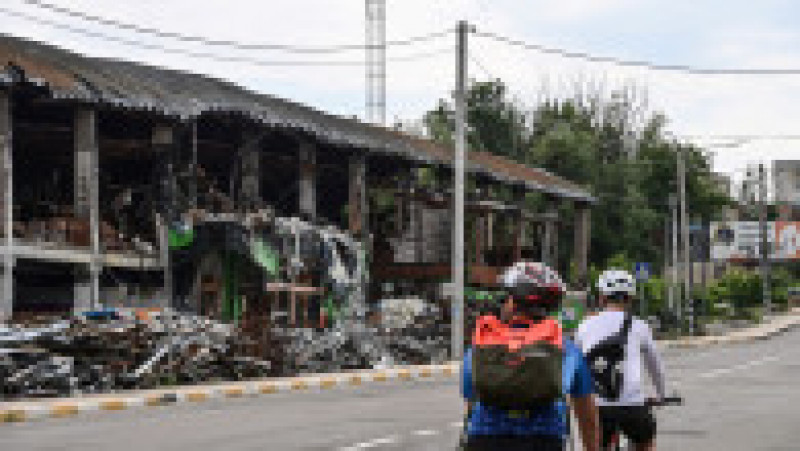 Doi bicicliști trec pe lângă un centru comercial care a fost distrus la începutul lunii martie 2022, lângă Irpin, pe strada Vokzalnaya, care leagă orașele ucrainene Bucha și Irpin. Foto: Profimedia Images | Poza 11 din 13