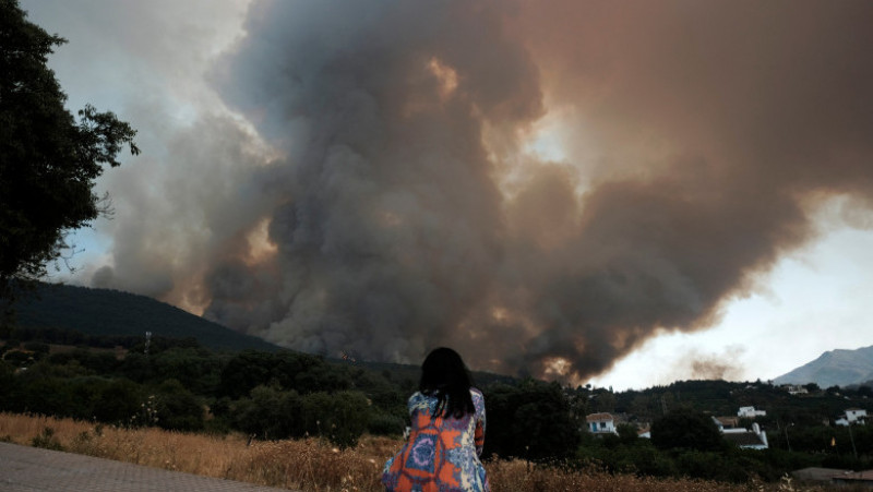 O femeie se uită la incendiile de pădure care se apropie de o zonă rezidențială din Malaga, Spania. Foto: Profimedia Images