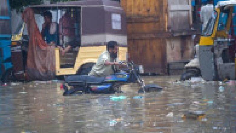 A man pushes his motorbike through a flooded street after heavy monsoon rainfall in Karachi on July 25, 2022.,Image: 709717212, License: Rights-managed, Restrictions: , Model Release: no, Credit line: Profimedia | Poza 11 din 13