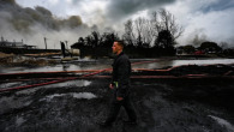Un pompier se plimbă prin zona afectată de incendiu, prin rămășițe de petrol dispersat. Foto: Profimedia Images | Poza 2 din 14