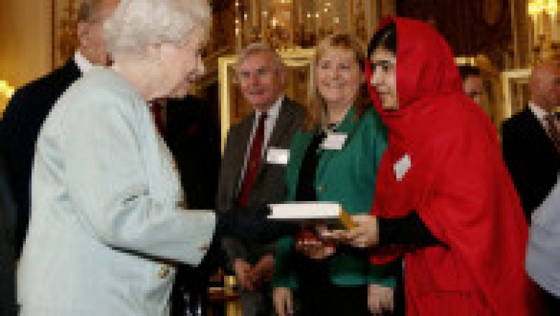  Malala Yousafzai (dreapta) îi oferă Reginei Elisabeta a II-a o copie a cărții ei, 18 octombrie 2013. Sursa foto: Profimedia Images | Poza 28 din 38