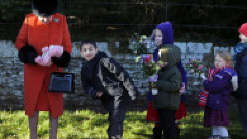 Copiii îi oferă flori și cadouri Reginei Elisabeta a II-a, după slujba tradițională de Crăciun. 25 decembrie 2013. Sursa foto: Profimedia Images | Poza 30 din 38