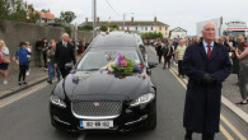 Sute de oameni s-au aliniat pe străzi pentru a-i aduce un omagiu regretatei cântărețe irlandeze Sinéad O’Connor marți, aplaudând cu lacrimi în ochi, cântând și aruncând flori în timp ce cortegiul funerar trecea pe lângă vechea ei casă din Bray, Irlanda. Procesiune funerară a fost publică, dar înmormântarea a fost privată. Sursa foto: Profimedia Images | Poza 1 din 7