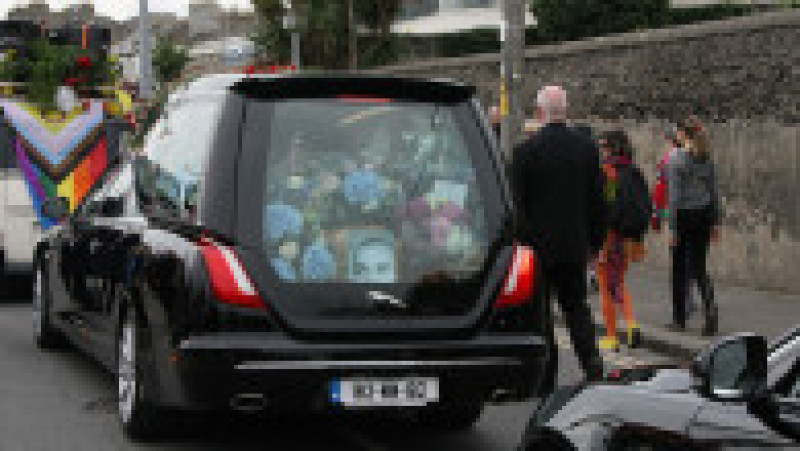 Sute de oameni s-au aliniat pe străzi pentru a-i aduce un omagiu regretatei cântărețe irlandeze Sinéad O’Connor marți, aplaudând cu lacrimi în ochi, cântând și aruncând flori în timp ce cortegiul funerar trecea pe lângă vechea ei casă din Bray, Irlanda. Procesiune funerară a fost publică, dar înmormântarea a fost privată. Sursa foto: Profimedia Images | Poza 2 din 7