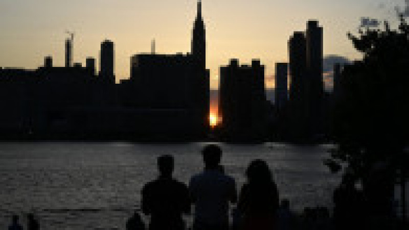 Mii de new-yorkezi s-au oprit cu telefoanele și camerele în mâini, pe trotuare, poduri și chiar în mijlocul drumului, ca să fotografieze cel mai frumos apus de soare, supranumit „Manhattanhenge”. FOTO Profimedia Images | Poza 4 din 15