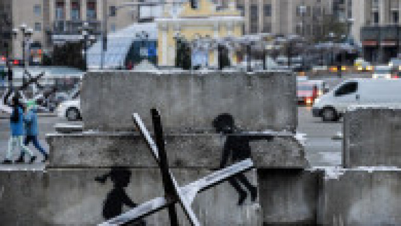 Pictură murală a lui Banksy de la Kiev care înfățișează doi copii care par că se dau pe leagăn - structura metalică este, însă, un "arici de oțel" antitanc. Foto: Profimedia Images | Poza 11 din 15