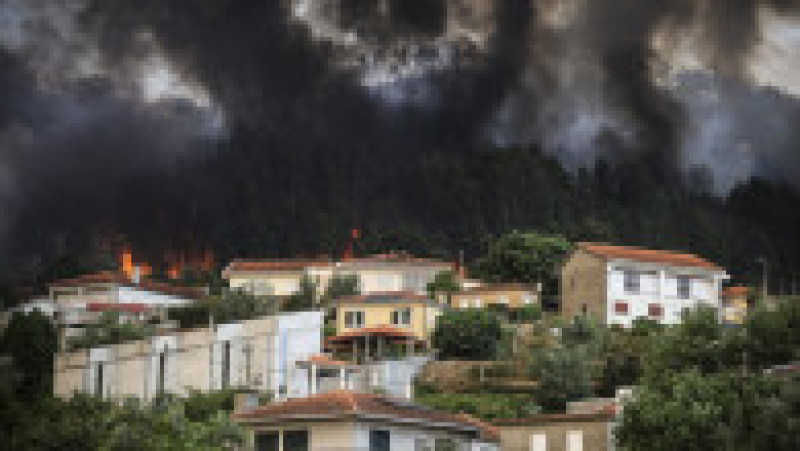 O fotografie realizată pe 29 iulie 2025 arată case lângă flăcări și fum care se ridică dintr-un incendiu forestier în Gondomar, nordul Portugaliei. Foto: Profimedia | Poza 5 din 9