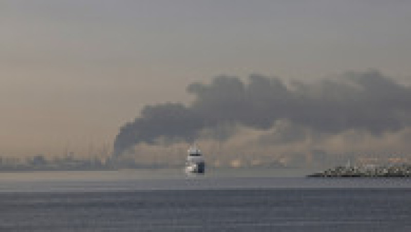 Un iaht navighează pe lângă un nor de fum care se ridică din portul Jebel Ali, în urma unui atac iranian raportat în Dubai, la 1 martie 2026 Foto: Profimedia | Poza 1 din 11