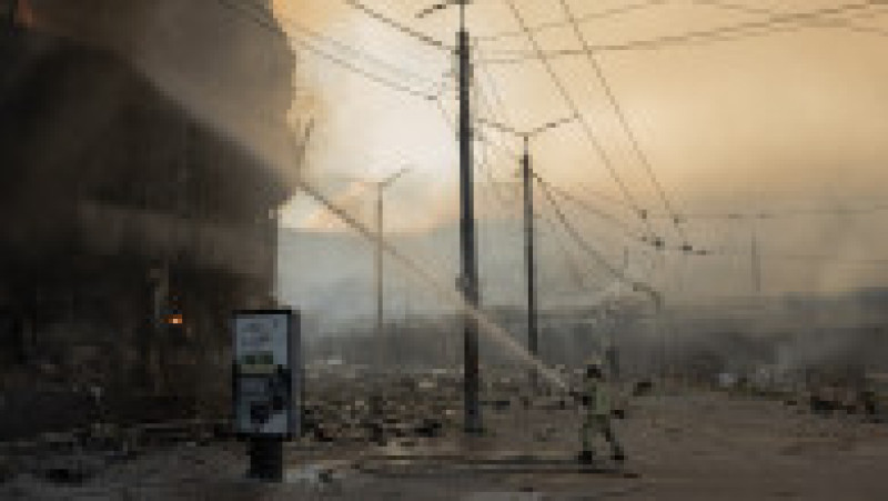 Un pompier ucrainean încearcă să stingă un incendiu la un centru comercial grav avariat, pe fondul norilor de fum care se ridică în fundal, în urma atacurilor rusești asupra Kievului din 24 mai 2026, în contextul invaziei rusești a Ucrainei. Foto: Profimedia | Poza 1 din 11