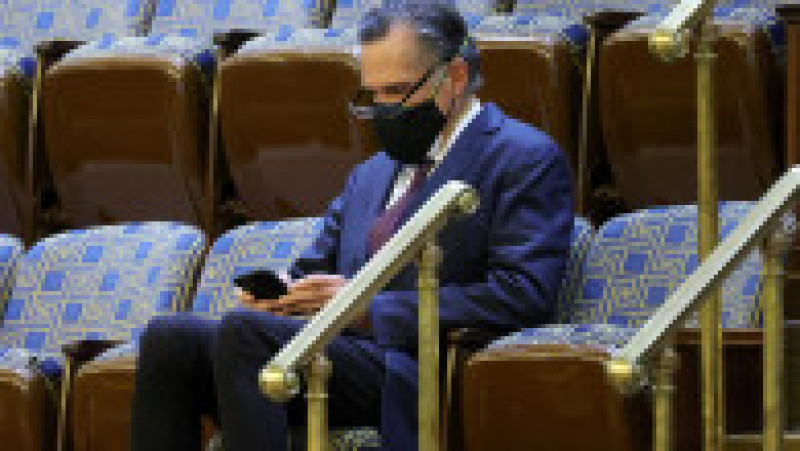 Senatorul republican Mitt Romney urmărește cu îngrijorare mesajele de pe telefon despre protestatarii care s-au sunat în fața clădirii. Foto: Profimedia Images | Poza 16 din 49