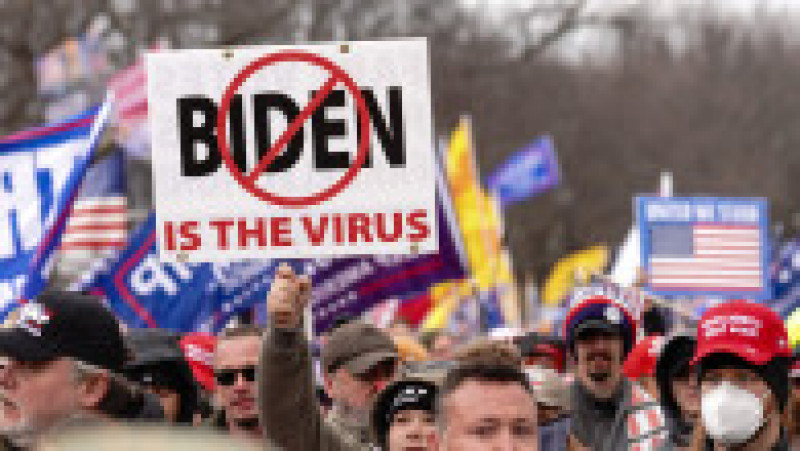 Un protestatar afișează o pancartă pe care scrie că Joe Biden „este virusul”. Foto: Profimedia Images | Poza 36 din 49