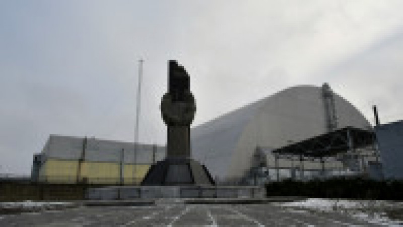 Imagine din 8 decembrie 2020. Monument ridicat în fața domului metalic ridicat deasupra sarcofagului care acoperă reactorul 4 al centralei de la Cernobîl. Sursa foto: Profimedia Images | Poza 8 din 14