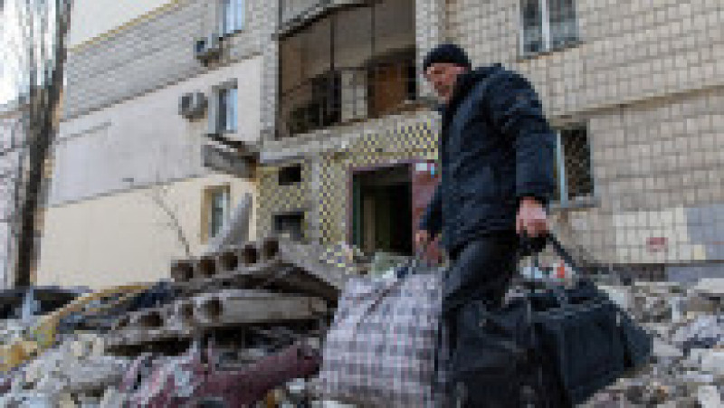 Un bărbat pleacă cu sacoșe de lucruri în care și-a adunat obiectele personale din apartamentul distrus de bombardamentele rusești. Foto: Profimedia Images | Poza 2 din 11