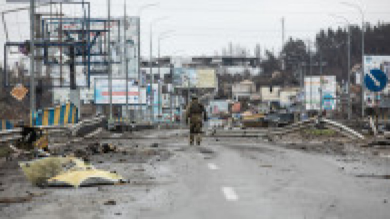 Un soldat ucrainean merge pe un drum printre victimele din Bucea, regiunea Kiev. Foto: Profimedia Images | Poza 1 din 9