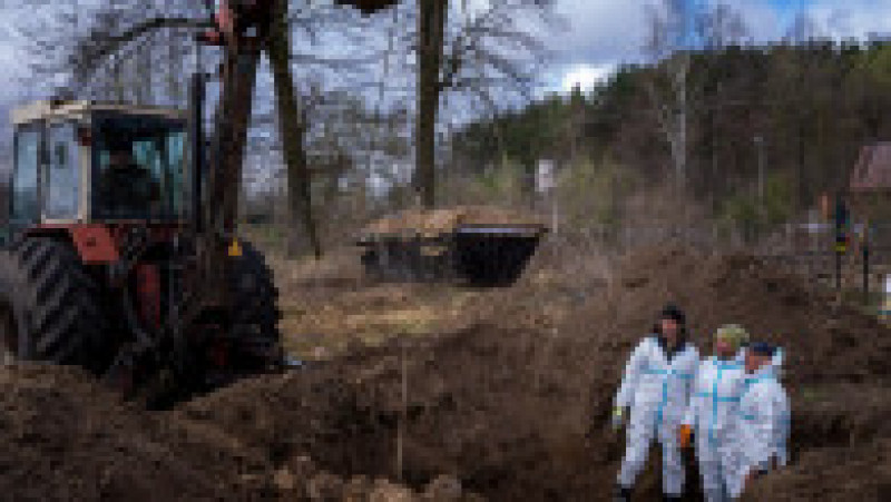 O macara ridică un sicriu în timp ce voluntarii scot pământul dintr-o groapă comună în timpul exhumării a patru civili uciși în regiunea Ivano-Frankivsk din Ucraina. Foto: Profimedia Images | Poza 2 din 11
