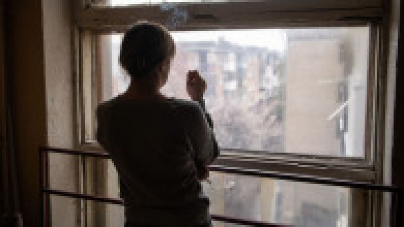 O ucraineancă privește din apartamentul ei la dezastrul cauzat de bombardamentele rusești în Harkov. Foto: Profimedia Images | Poza 7 din 12