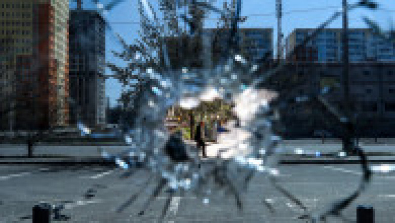 Un bărbat este văzut printr-o gaură de glonț de pe geamul unui supermarket din Saltivka, localitate aflată în regiunea Harkov. Foto: Profimedia Images | Poza 6 din 13