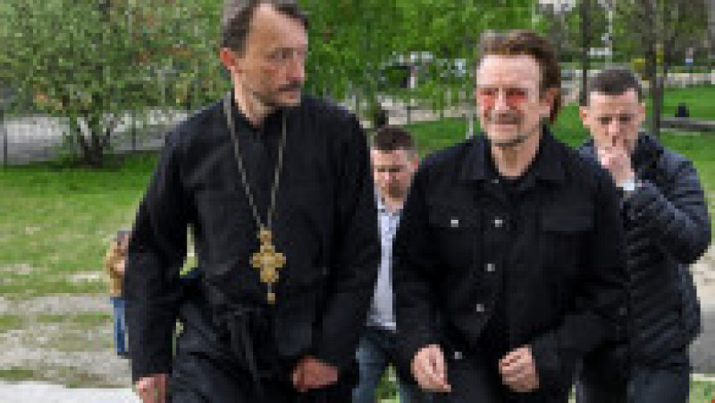 Preotul Andrii Holovine îl însoțește pe Bono la groapa comună de lângă biserica de la Bucha Foto: Profimedia Images | Poza 13 din 18
