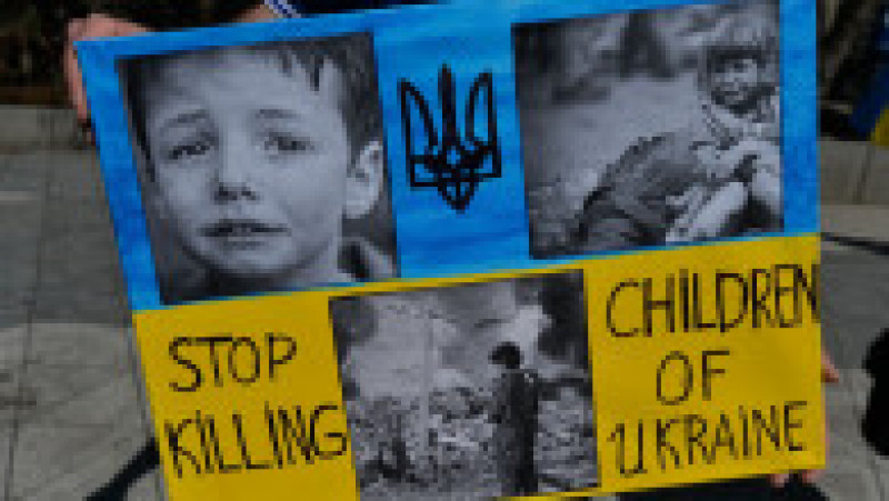 O pancartă cu mesajul „nu mai ucideți copiii ucraineni” a fost afișat de către un protestatar la o manifestație împotriva războiului desfășurată în Canada. Foto: Profimedia Images | Poza 12 din 12