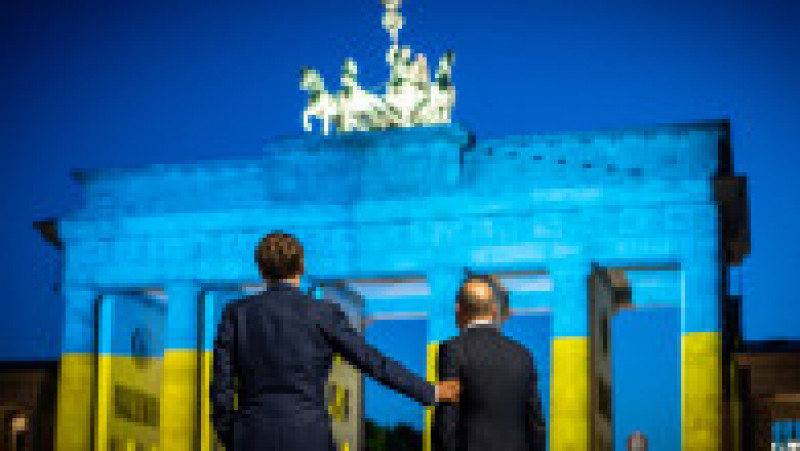 Președintele francez și cancelarul german în fața porții Brandenburg din Berlin, decorată în culorile drapelului ucrainean. Foto: Profimedia Images | Poza 12 din 12