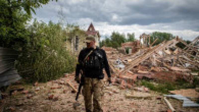 Un soldat al apărării teritoriului ucrainean trece pe lângă ruinele unei clădiri lovite de bombardamente la periferia regiunii separatiste Donețk. Foto: Profimedia Images | Poza 6 din 12