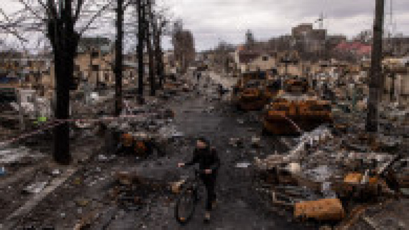 Un civil ucrainean merge printre epavele unor blindate ruseşti distruse în Bucha. Foto: Profimedia Images | Poza 3 din 21