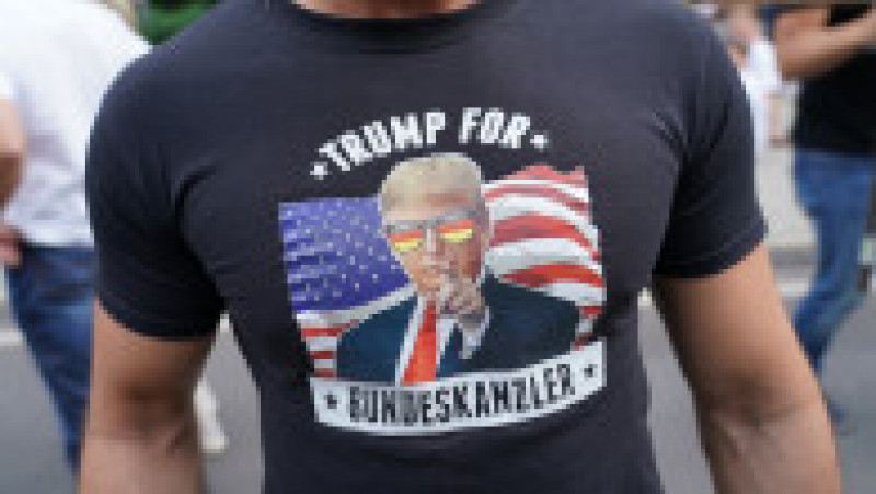 Un bărbat poartă un tricou inscripționat cu mesajul „Trump pentru funcția de cancelar federal” și o fotografie a președintelui SUA, la protestele extremiștilor din Berlin. Foto: Getty Images | Poza 5 din 5
