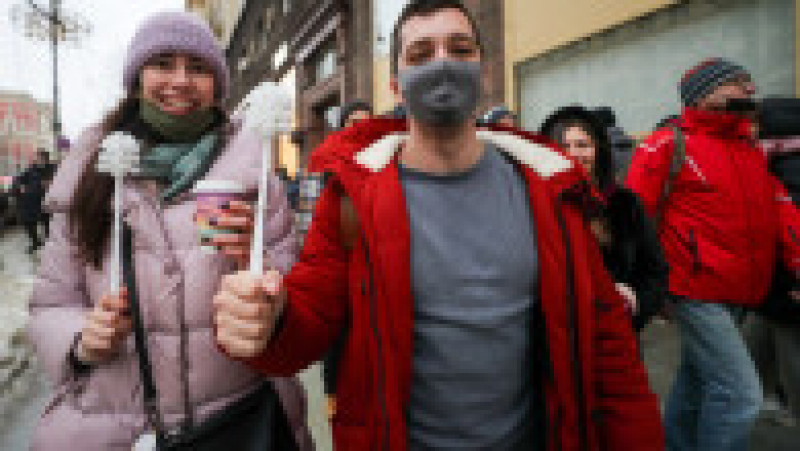 23 ianuarie 2021, Moscova: Doi tineri merg pe stradă râzând și ținând în mâini perii de WC în timp ce participă la o demonstrație în favoarea lui Alexei Navalnîi | Poza 5 din 6