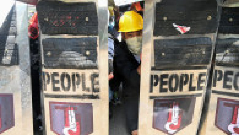 Un manifestant se uită printre scuturi. Sursa foto: Profimedia Images | Poza 13 din 19