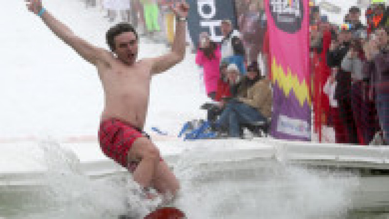 Un tânăr pe snowboard sare într-o piscină la festivalul organizat pe platoul montan Rosa Hutor din Soci Foto: Profimedia | Poza 7 din 7