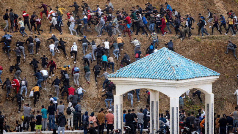 Sute de migranți încearcă să evite poliția de frontieră a Marocului pentru a intra în exclava spaniolă Ceuta. Foto: Profimedia Images