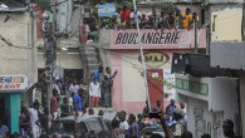 Mulțimea înconjoară o mașină de poliție care transportă doi suspecți arestați în suburbia Petionville din Port au Prince. Sursa foto: Profimedia Images | Poza 13 din 38