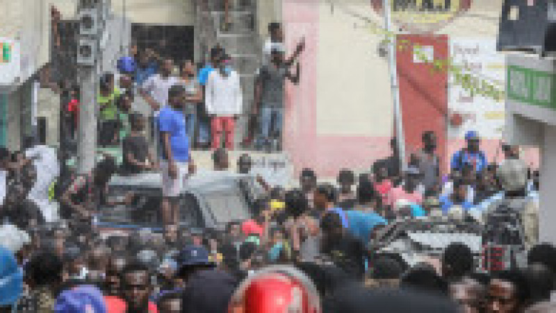 Mulțimea înconjoară o mașină de poliție care transportă doi suspecți arestați în suburbia Petionville din Port au Prince. Sursa foto: Profimedia Images | Poza 1 din 26