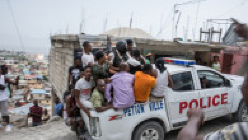 O mașină de poliție cu agenți și civili se îndreaptă către mahalaua Jalousie, lângă Port au Prince, unde au fost arestați mai mulți suspecți în cazul uciderii președintelui haitian. Sursa foto: Profimedia Images | Poza 16 din 38