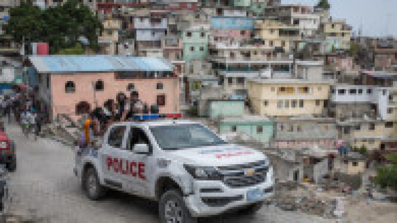 O mașină de poliție cu agenți și civili se îndreaptă către mahalaua Jalousie, lângă Port au Prince, unde au fost arestați mai mulți suspecți în cazul uciderii președintelui haitian. Sursa foto: Profimedia Images | Poza 23 din 26