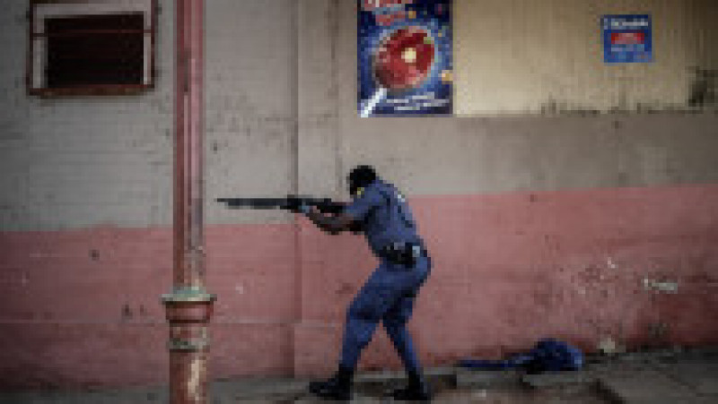 Un polițist din Johannesburg trage cu gloanțe de cauciuc în protestatari. Sursa foto: Profimedia Images | Poza 2 din 33