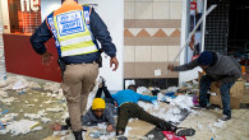 Un polițist sud-african calcă pe mâna unui presupus jefuitor, în mall-ul Bara din Soweto, Johannesburg. Sursa foto: Profimedia Images | Poza 20 din 33