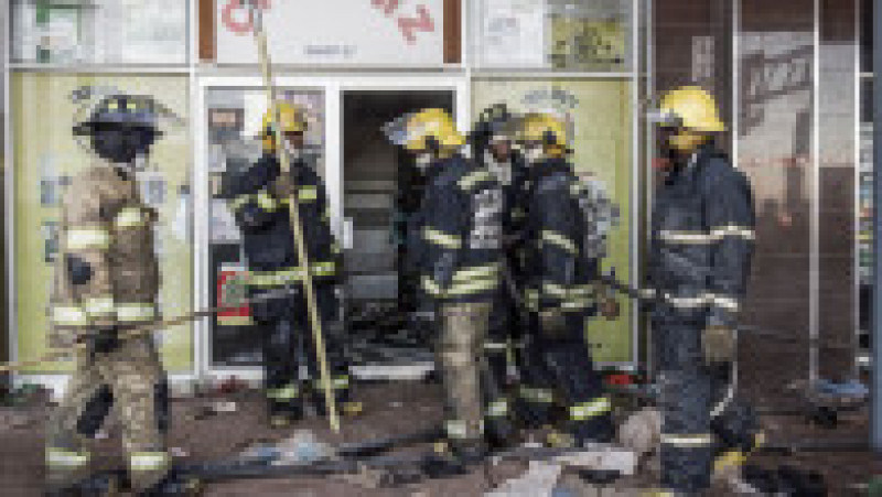 Pompierii sud-africani se adună în afara mall-ului vandalizat din Vosloorus, la periferia orașului Johannesburg. Sursa foto: Profimedia Images | Poza 27 din 33